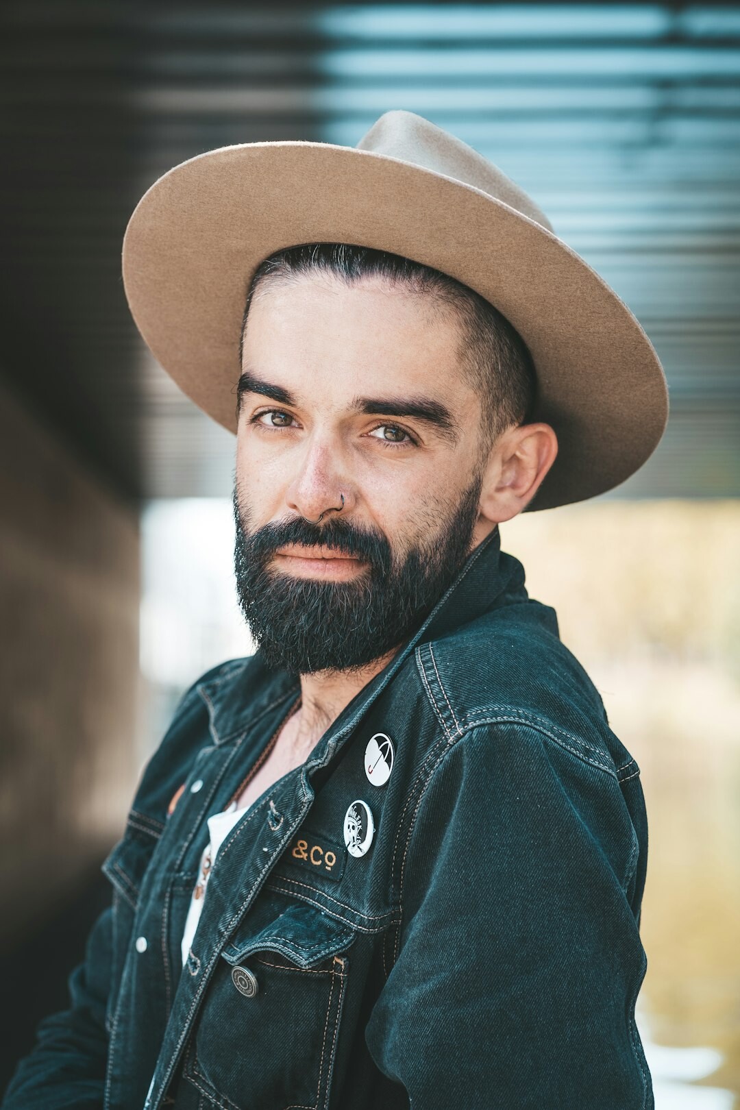 Studio portrait of a French man in his thirties with a beard, wearing a denim shirt